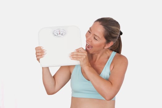 Close_up of a woman holding a bathroom scale and looking excited