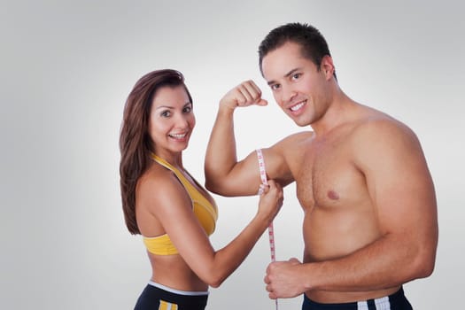 Woman measuring biceps of a man with a tape measure