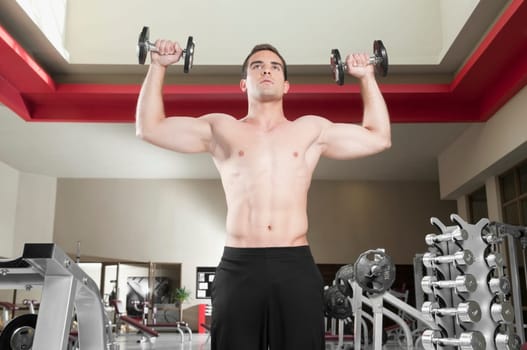Man exercising with dumbbells in a gym