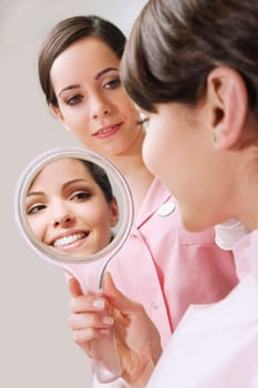Woman looking into a mirror in dentistŽs office