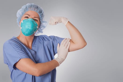 Female surgeon wearing flu mask and showing biceps