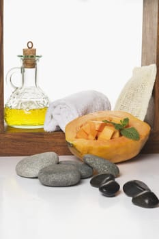Close_up of papaya with body oil and spa stones