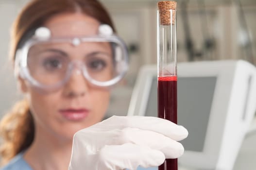 Female lab technician analyzing a blood sample in a test tube