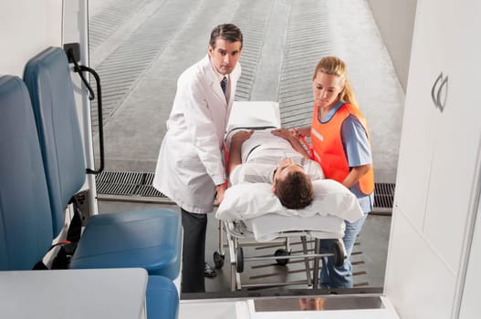Paramedics leading a patient on a gurney into an ambulance