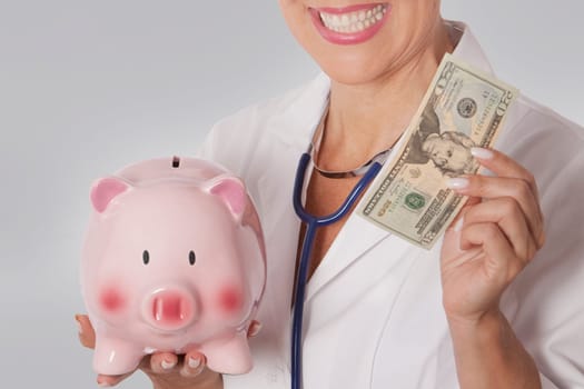Female doctor holding a currency note and a piggy bank
