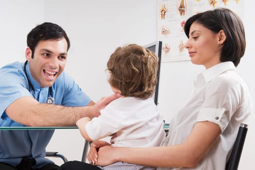 Doctor examining a baby boy sitting on his motherŽs lap