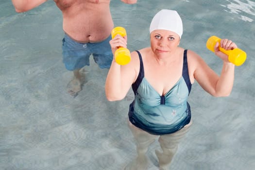Couple exercising with dumbbells in a swimming pool