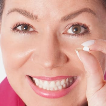 Woman holding a pill and smiling