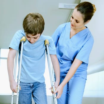 Female nurse assisting a boy on crutches