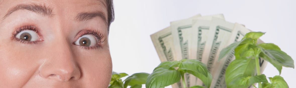 Woman looking shocked with money growing on a plant
