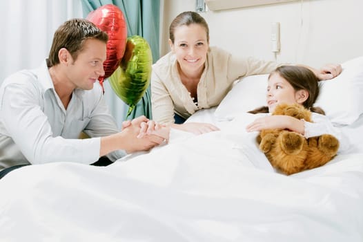 Girl on a hospital bed with her parents beside her