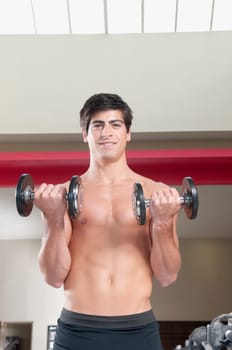 Portrait of a man exercising with dumbbells in a gym