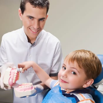Boy learning how to brush teeth with the help of dentures in a dentistŽs office
