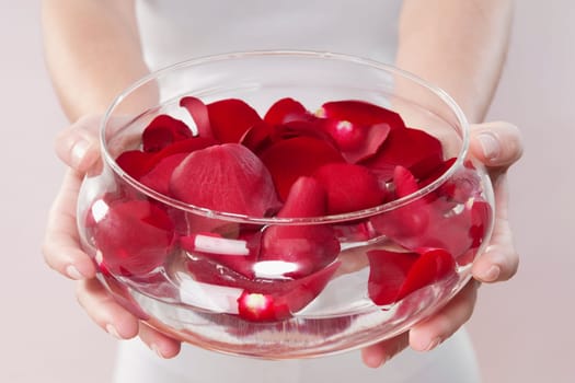 Mid section view of a woman holding a bowl of rose petals