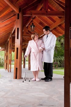 Doctor assisting a patient in walking in a rehabilitation centre