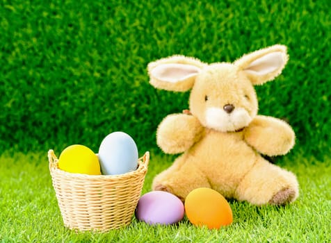 Easter bunny toy and Easter eggs in basket on green grass