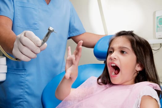 Scared girl looking at dental drill in a dentistŽs hand