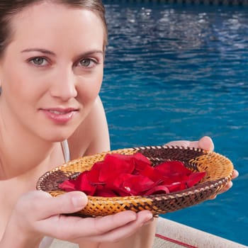 Woman holding a plate of rose petals at the poolside
