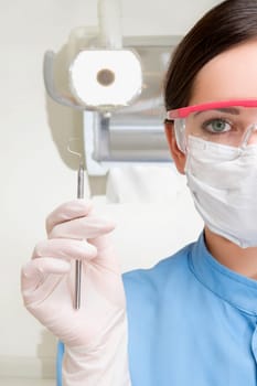 Portrait of a female dentist holding a dental scaler