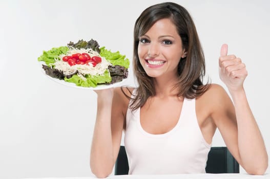 Woman making a thumbs up sign with a plate of salad