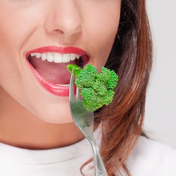 Close_up of a woman eating broccoli