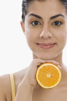 Portrait of a woman holding a half of orange