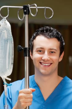 Doctor holding a saline drip stand and smiling