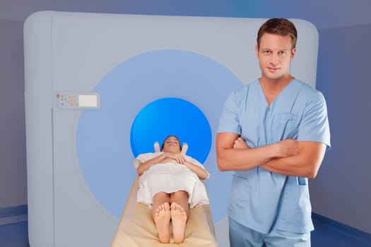 Healthcare worker standing beside a patient undergoing an MRI scan