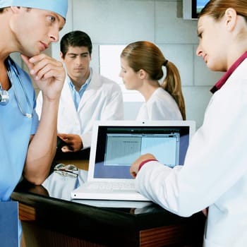 Female doctor and a surgeon discussing a medical report on a laptop