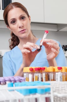 Female lab technician analyzing a blood sample in a test tube