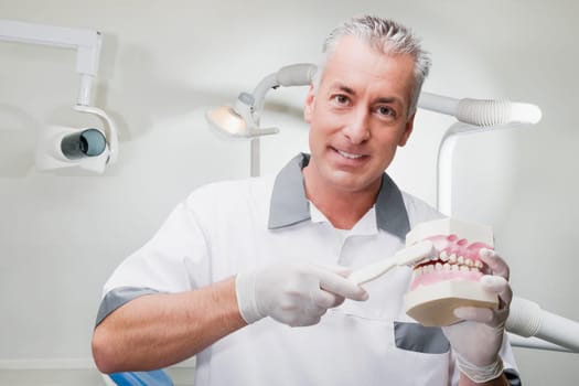 Dentist using a toothbrush on dentures