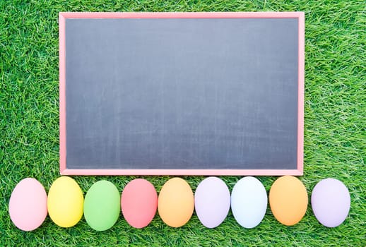 Close up Colorful easter eggs on green grass and blackboard mockup with copy space