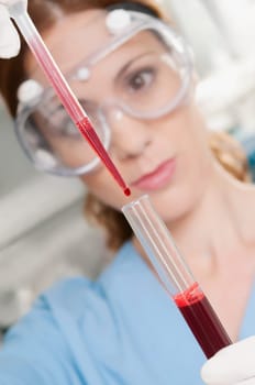 Female lab technician analyzing a blood sample in a test tube