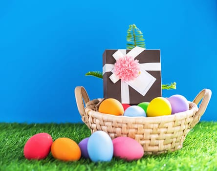 Colorful easter eggs in the basket on green grass background with copy space