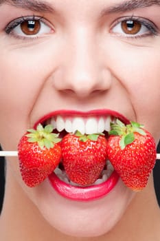 Close_up of a woman biting strawberries on a skewer