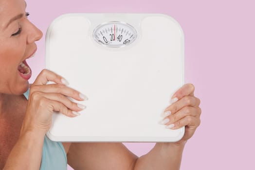 Close_up of a woman holding a bathroom scale and looking excited