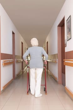 Rear view of a woman walking with the help of walker