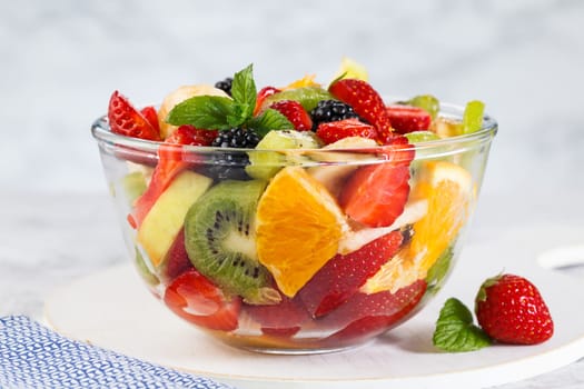 Healthy fresh fruit salad in a bowl on a gray background. .