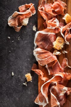 Slices of Prosciutto on dark  background. Top view.