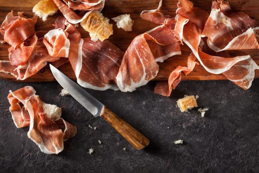 Slices of Prosciutto on dark  background. Top view.