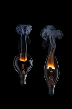 Collection of light bulbs with fire and smoke on black background.