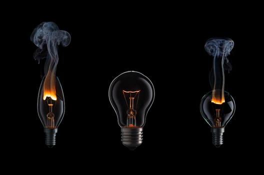 Collection of light bulbs with fire and smoke on black background.