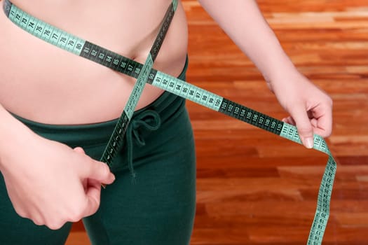 Woman measuring her waist with a tape measure