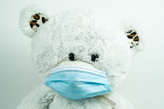 Masked teddy bear with surgical mask on white background