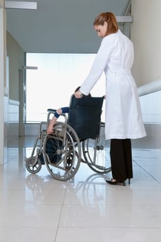 Female doctor pushing a patient in a wheelchair