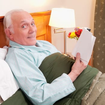 Man reading a book in nursing home and smiling