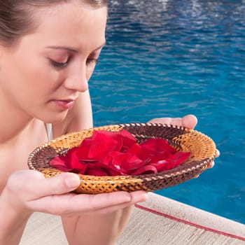 Woman holding a plate of rose petals at the poolside