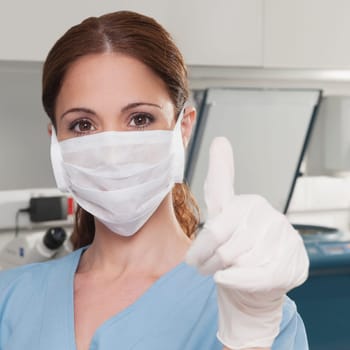 Female lab technician showing thumbs up sign in a laboratory