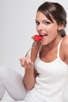 Woman eating a strawberry on a fork