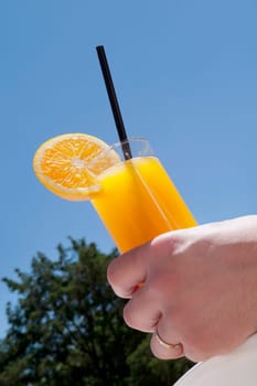 PersonŽs hand holding a glass of orange juice